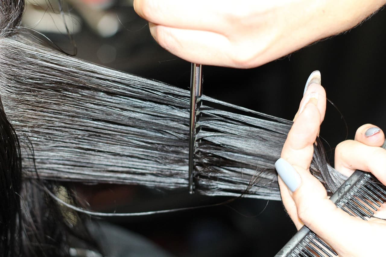 Stylist combing out a section of long dark hair